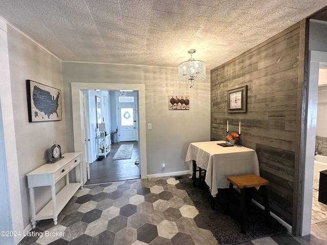 dining area with an inviting chandelier, crown molding, a textured ceiling, and wood walls