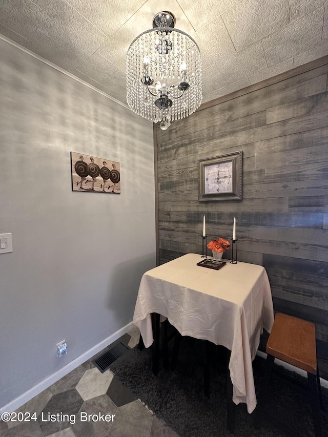 dining space with a chandelier and wood walls