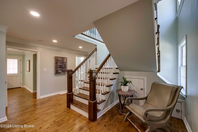 living area with light wood-type flooring and ornamental molding