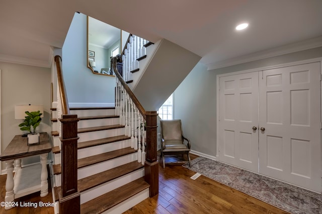 staircase with wood-type flooring and ornamental molding