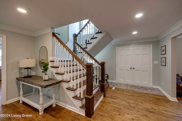 stairs featuring light wood-type flooring and ornamental molding