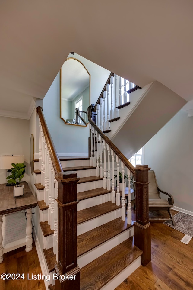 stairs with crown molding and hardwood / wood-style floors