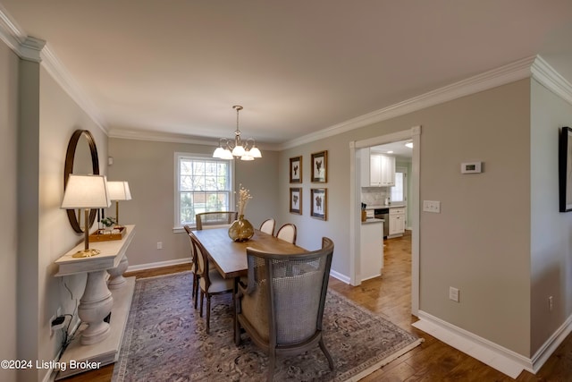 dining area with wood-type flooring, a notable chandelier, and ornamental molding