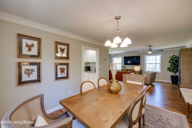 dining area with hardwood / wood-style flooring, ceiling fan with notable chandelier, and crown molding