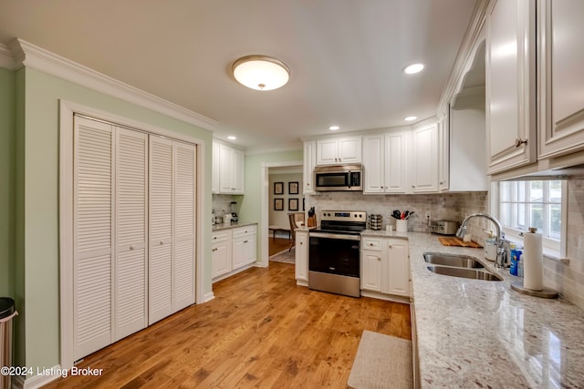 kitchen featuring white cabinetry, light hardwood / wood-style flooring, light stone countertops, appliances with stainless steel finishes, and sink