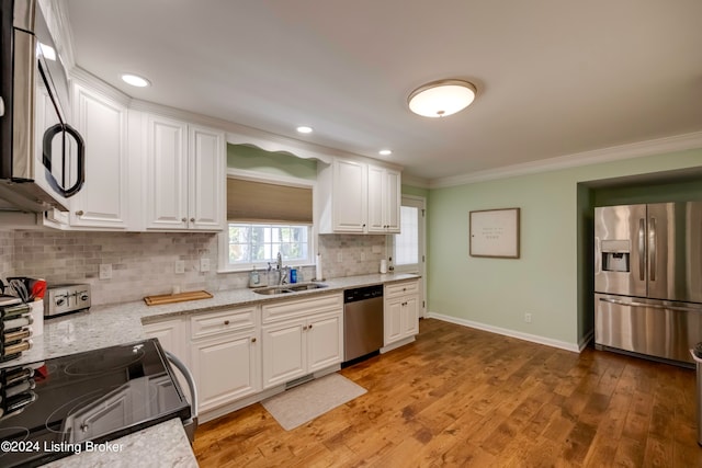 kitchen with tasteful backsplash, white cabinets, light wood-type flooring, sink, and appliances with stainless steel finishes