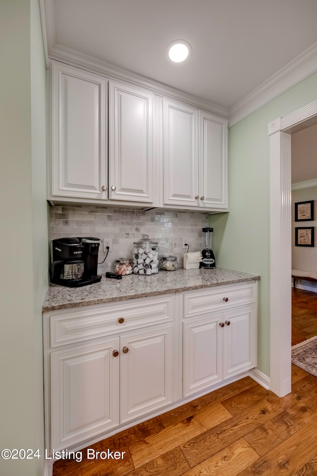 interior space featuring white cabinetry, decorative backsplash, light wood-type flooring, and light stone counters