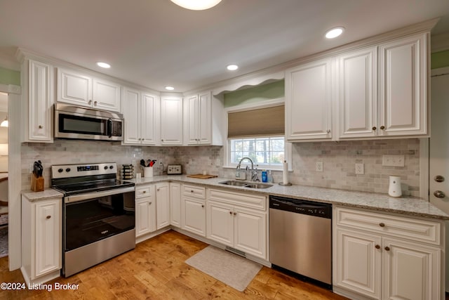 kitchen with stainless steel appliances, light hardwood / wood-style floors, backsplash, and sink