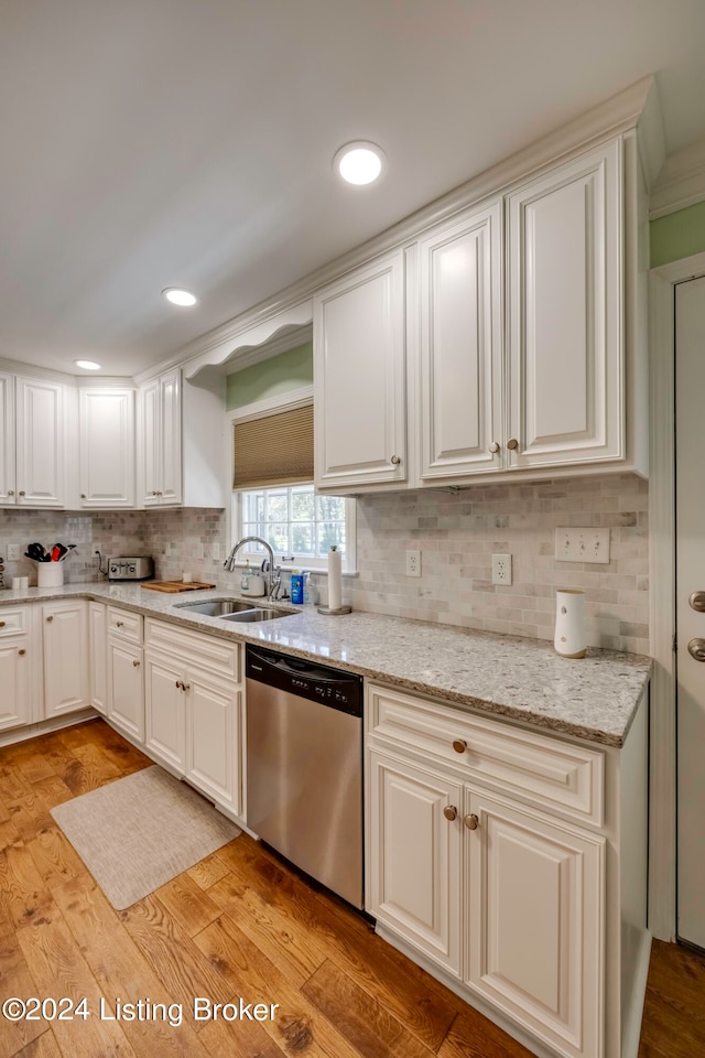 kitchen with sink, backsplash, light wood-type flooring, light stone countertops, and dishwasher