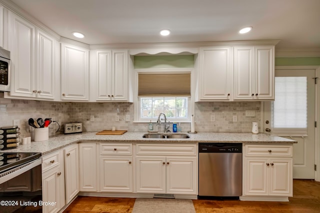 kitchen featuring appliances with stainless steel finishes, backsplash, light stone countertops, and sink