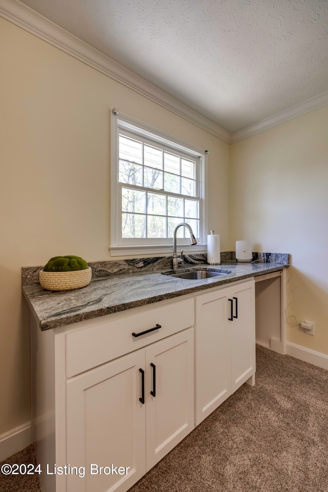 kitchen with white cabinets, dark carpet, sink, and a textured ceiling