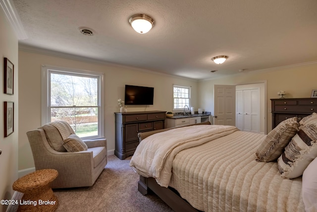 bedroom with a textured ceiling, a closet, ornamental molding, and light colored carpet