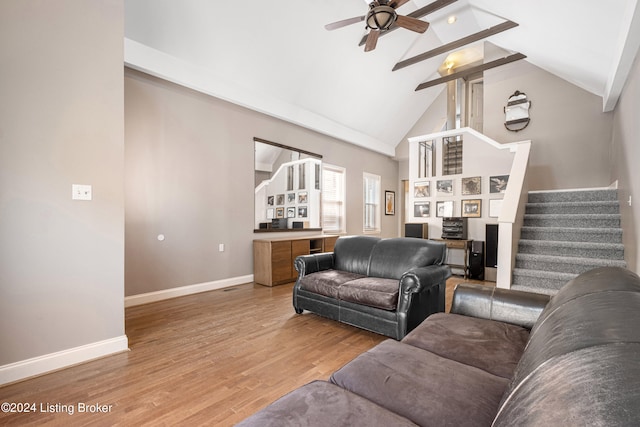 living room featuring a ceiling fan, wood finished floors, high vaulted ceiling, baseboards, and stairs