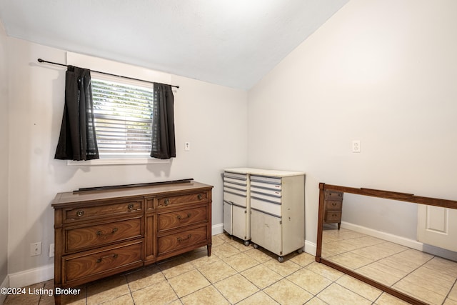 bedroom with baseboards, vaulted ceiling, and light tile patterned flooring