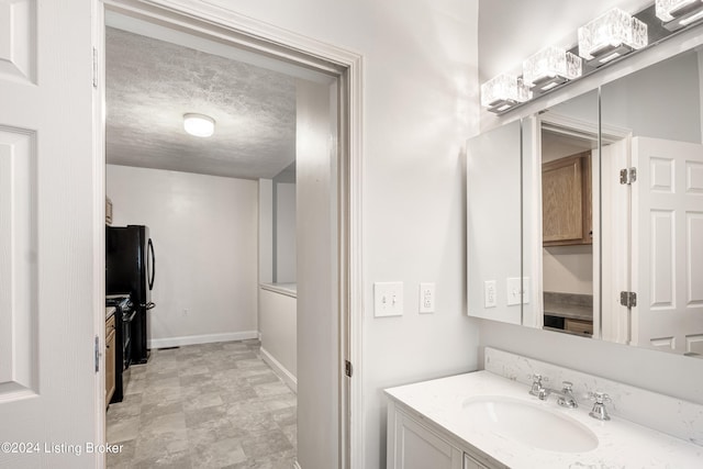 bathroom with baseboards, a textured ceiling, and vanity