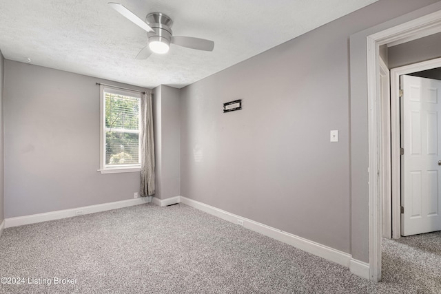 carpeted empty room featuring a textured ceiling, ceiling fan, and baseboards