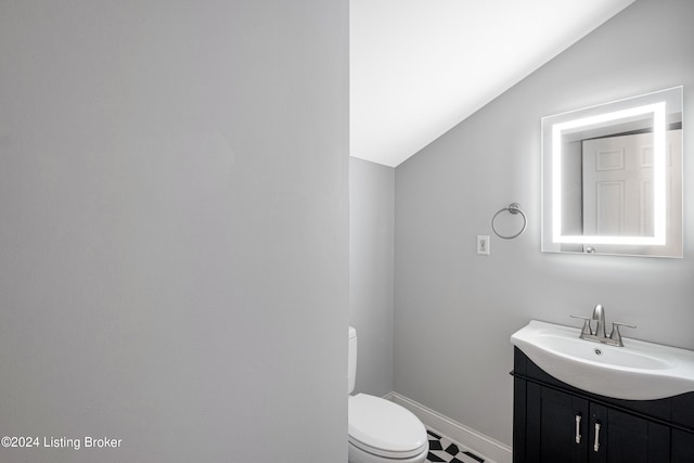 half bath with lofted ceiling, baseboards, vanity, and toilet