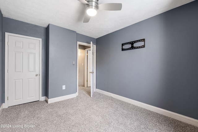 unfurnished bedroom with a textured ceiling, baseboards, a ceiling fan, and light colored carpet