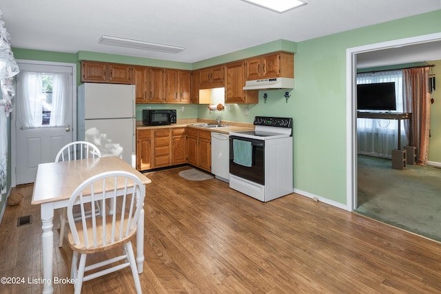 kitchen with light wood-type flooring, white appliances, and sink