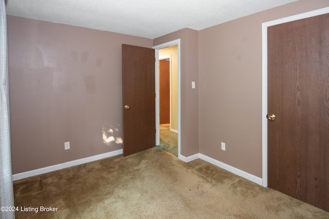 unfurnished bedroom featuring carpet floors, a closet, and a textured ceiling