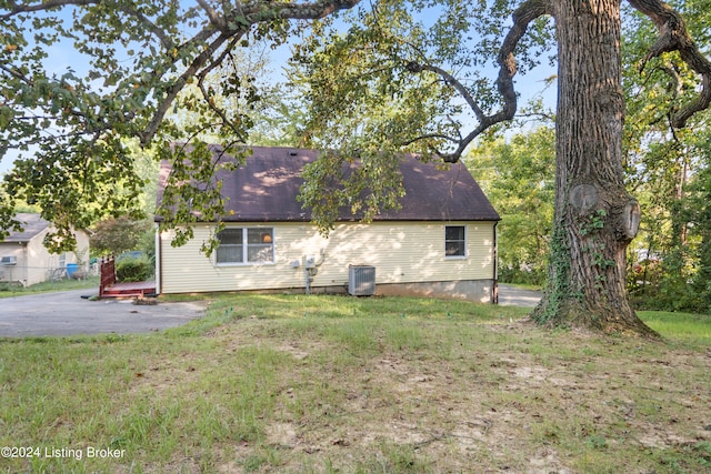 rear view of house featuring a lawn and central AC unit