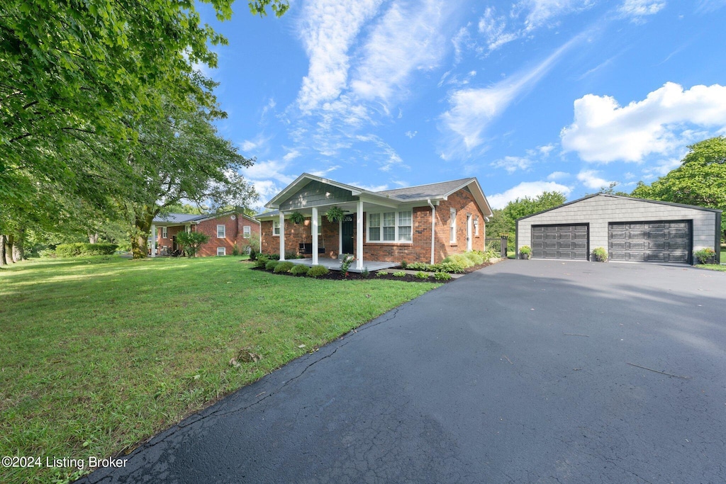 view of front facade with a garage, a front lawn, an outdoor structure, and a porch