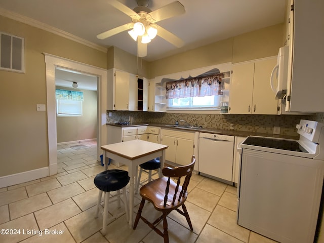 kitchen featuring sink, white appliances, tasteful backsplash, a healthy amount of sunlight, and white cabinets