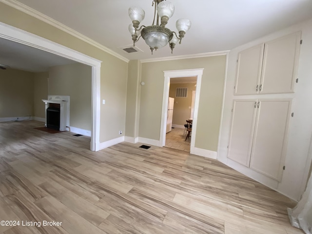 unfurnished dining area with crown molding, an inviting chandelier, and light wood-type flooring