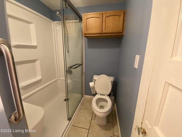 bathroom featuring tile patterned flooring, toilet, and walk in shower