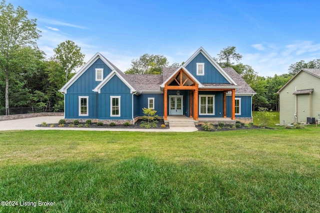 view of front of home featuring a shingled roof, cooling unit, board and batten siding, and a front yard