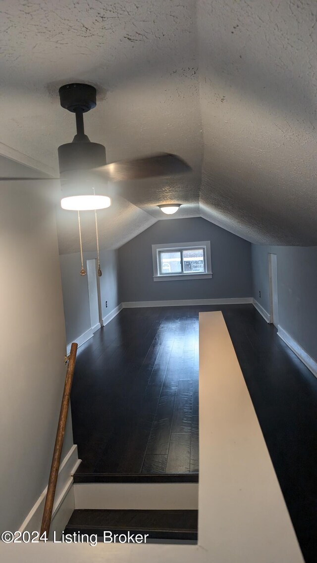 bonus room with lofted ceiling, hardwood / wood-style floors, and a textured ceiling