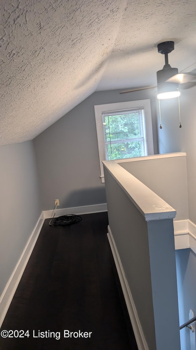 hall with lofted ceiling and a textured ceiling