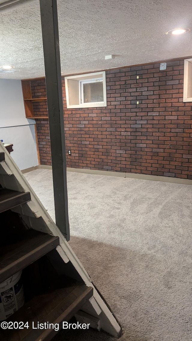 basement with brick wall, carpet, and a textured ceiling