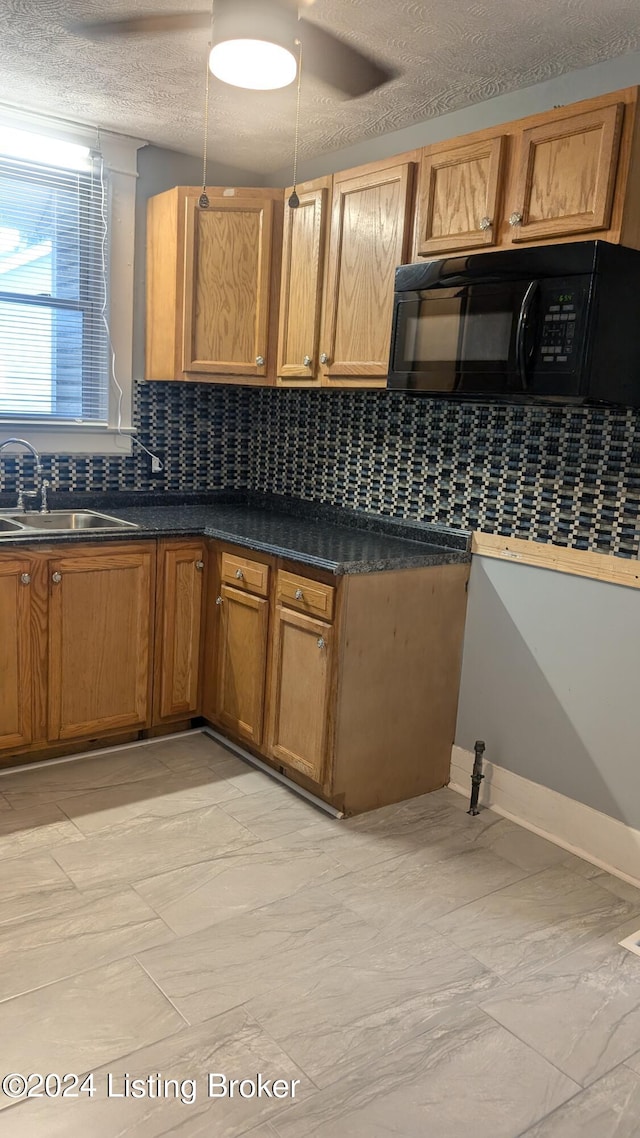 kitchen featuring light tile patterned flooring, backsplash, sink, and a textured ceiling