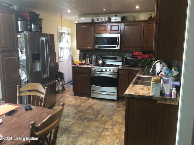 kitchen featuring tasteful backsplash, stainless steel appliances, sink, dark tile patterned flooring, and dark brown cabinetry