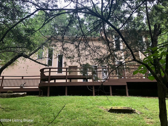 back of property featuring a wooden deck and a yard