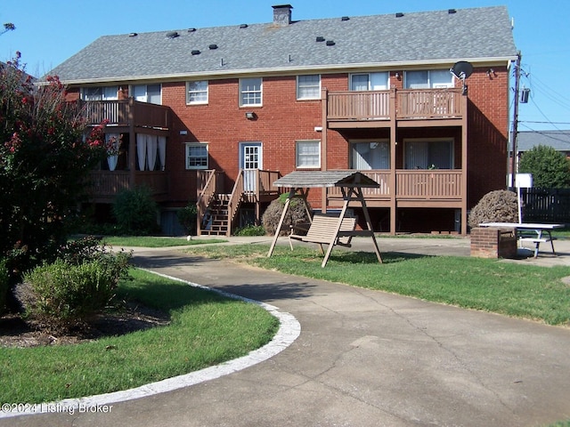 rear view of house with a balcony and a yard