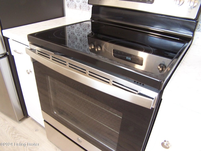 room details with light hardwood / wood-style flooring and stainless steel range with electric cooktop