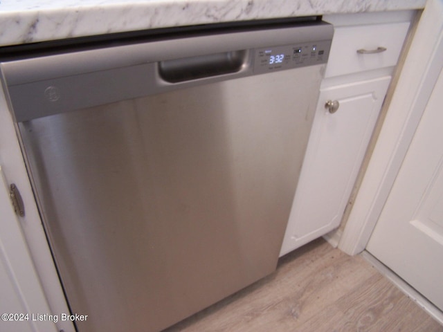 details featuring light wood-type flooring, stainless steel dishwasher, and white cabinetry