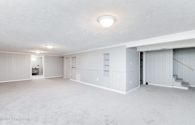 basement with carpet flooring, ornamental molding, and a textured ceiling