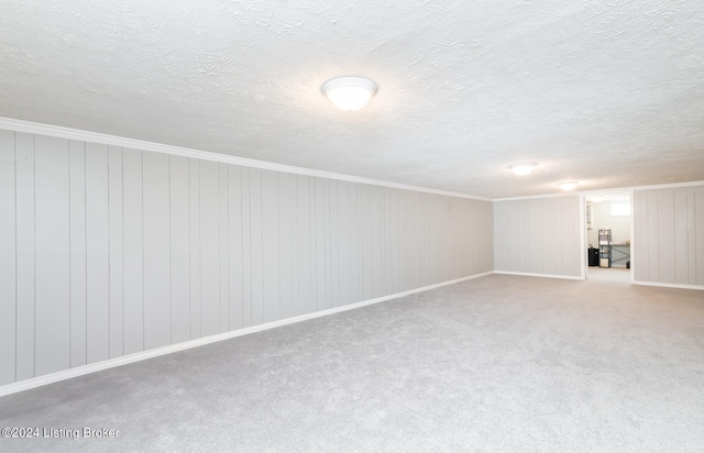 basement featuring a textured ceiling, carpet, and ornamental molding