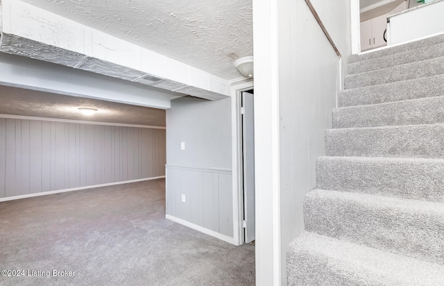 stairs with a textured ceiling and carpet flooring