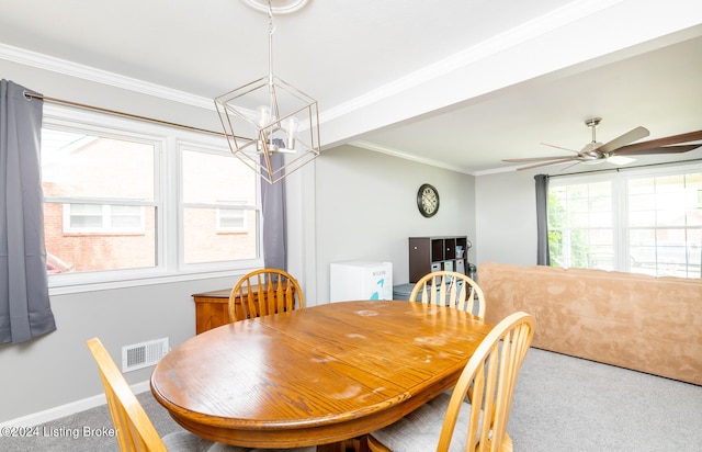 carpeted dining room with ceiling fan with notable chandelier and crown molding