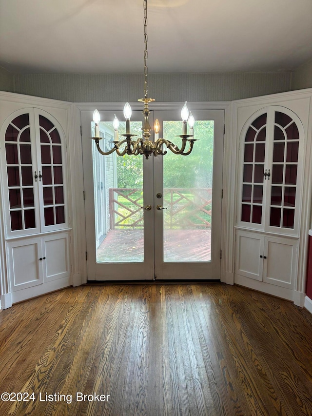 unfurnished dining area featuring an inviting chandelier, hardwood / wood-style flooring, and french doors