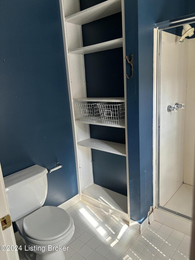 bathroom with tile patterned flooring, walk in shower, and toilet