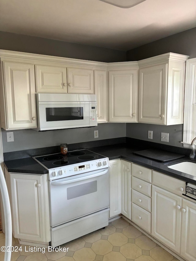 kitchen featuring white cabinets, sink, white appliances, and light tile patterned floors