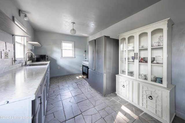 kitchen with a healthy amount of sunlight, stainless steel appliances, sink, and hanging light fixtures