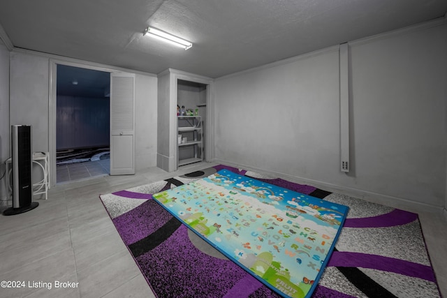 basement with a textured ceiling and light tile patterned floors