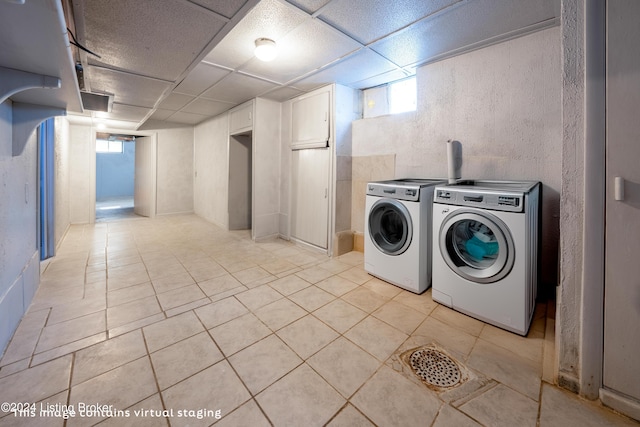 laundry room with a wealth of natural light, light tile patterned floors, and washer and clothes dryer