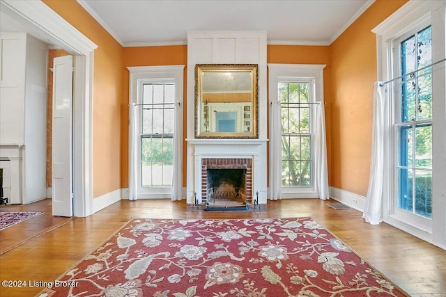 living room with ornamental molding, hardwood / wood-style floors, and a brick fireplace